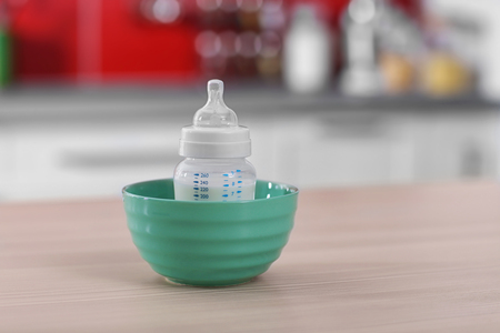 Baby bottle in bowl on kitchen tableの写真素材