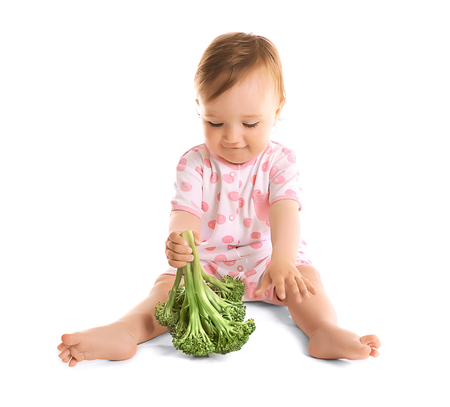 Cute baby girl with broccoli, isolated on whiteの写真素材
