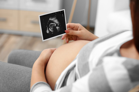 Young pregnant woman looking at ultrasound photoの写真素材