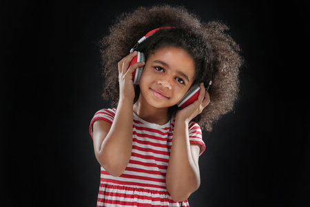 Afro-American little girl with headphones on dark backgroundの写真素材