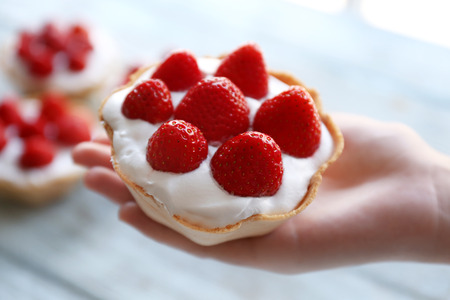 Female hand holding strawberry cake, closeupの写真素材