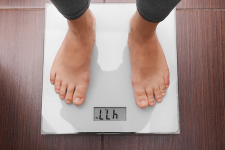 Female bare feet standing on a scales in bathroomの写真素材