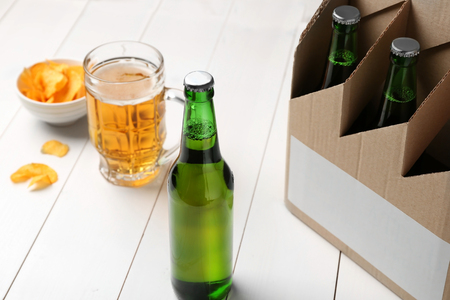 Paper beer package with mug and chips on wooden backgroundの写真素材