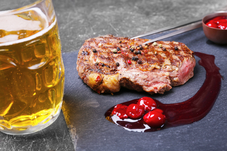 Tasty juicy steak with sauce and beer on slate plateの写真素材
