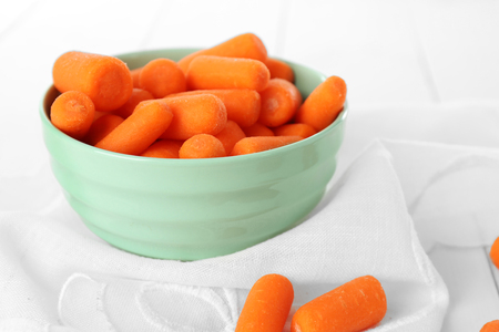 Small baby carrots in soup plate on napkinの写真素材