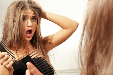 Mirror reflection of young woman making hairdoの写真素材