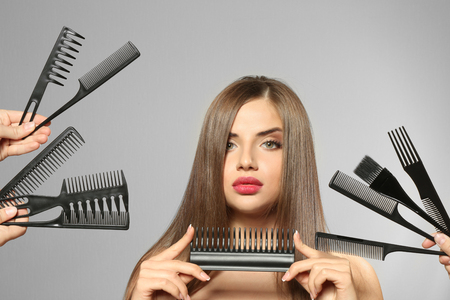 Young woman with combs on light backgroundの写真素材