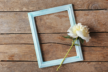 Beautiful flower and photo frame on wooden backgroundの写真素材