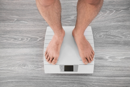 Man standing on weight scaleの写真素材