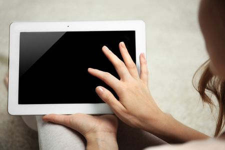 Woman holding tablet on blurred carpet backgroundの写真素材
