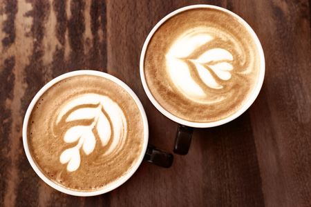 Cups of coffee with latte art on wooden backgroundの写真素材