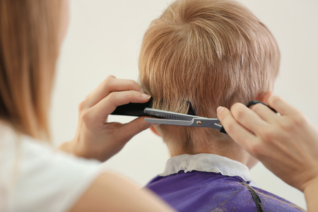 Hairdresser's hands making hairstyle to childの写真素材