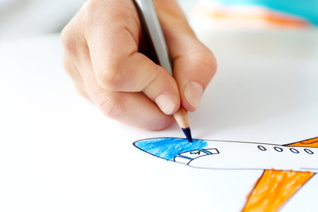 Child's hand drawing picture on paper