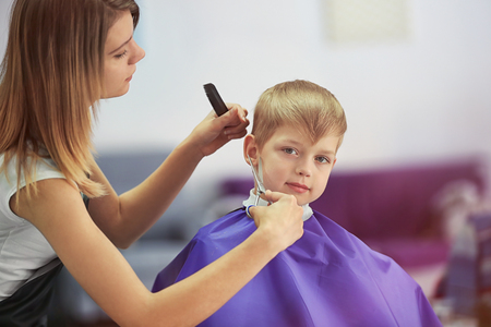 Hairdresser making hairstyle to childの写真素材