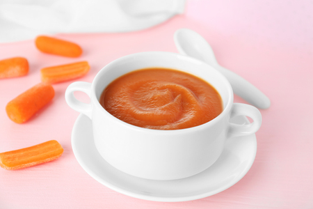 Carrot puree in soup plate on pink backgroundの写真素材