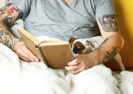 Man with cute dog reading bookの写真素材