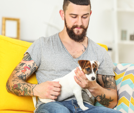 Handsome man with cute dog at homeの写真素材
