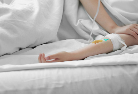 Girl hand with drip infusion on bedの写真素材