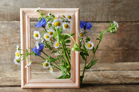 Retro frame with chamomile and bluettes on wooden backgroundの写真素材