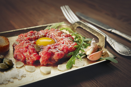 Steak tartar with chopped onion and pickles on a trayの写真素材