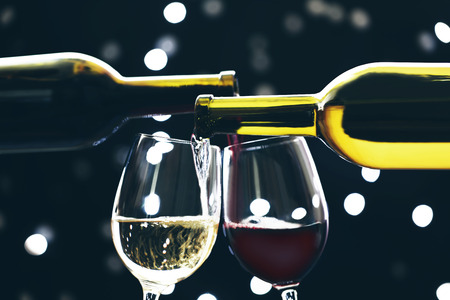 Red and white wine pouring in glass on bokeh backgroundの写真素材