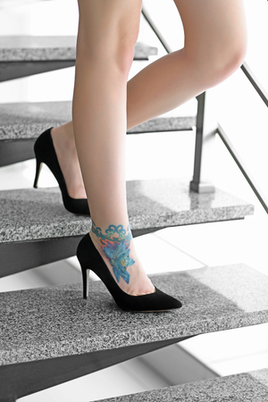Woman with tattoo on her leg in high heeled shoes on the stairsの写真素材