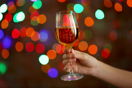 White wine glass in female hand on bokeh backgroundの写真素材