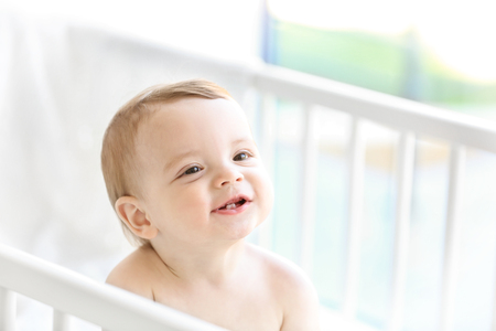 Cute baby sitting in the bedの写真素材