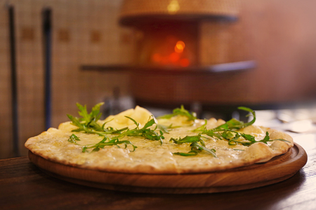 Tasty pizza on the table against wood-burning stoveの写真素材