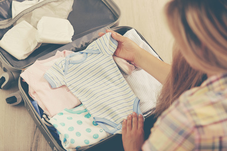 Pregnant woman packing suitcase for maternity hospital at homeの写真素材