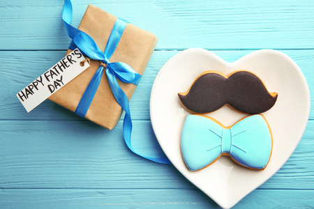 Happy Father's Day concept. Plate with tasty cookies and gift box on wooden backgroundの写真素材