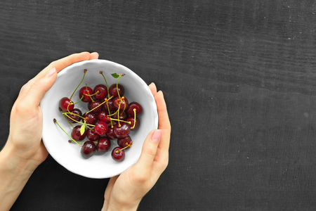 Human hands holding cherries, top viewの写真素材
