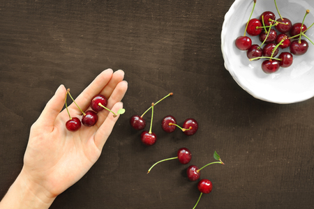 Human hand holding cherries, top viewの写真素材