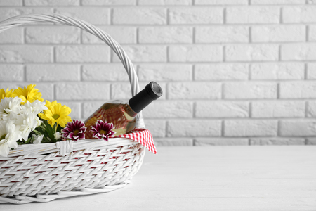 Wine bottle with flowers in basket on light backgroundの写真素材