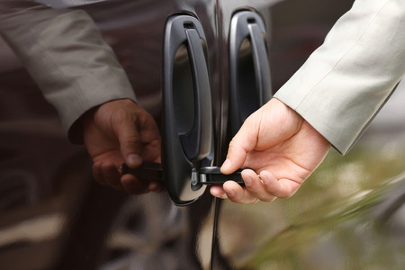 Male hand opening car door with keyの写真素材