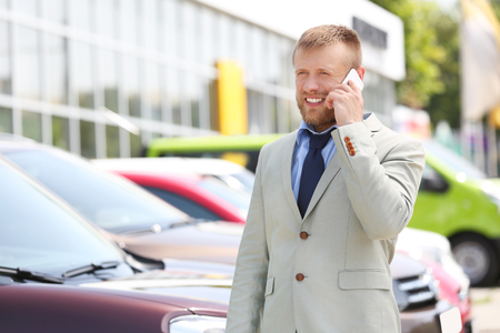 Man talking on phone on new cars backgroundの写真素材