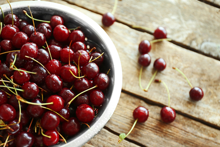 Cherries in colander on wooden tableの写真素材