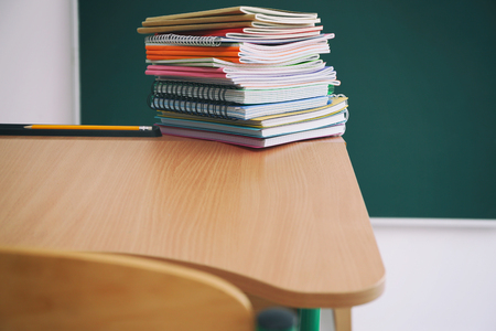 Stacked school notebooks on blackboard backgroundの写真素材