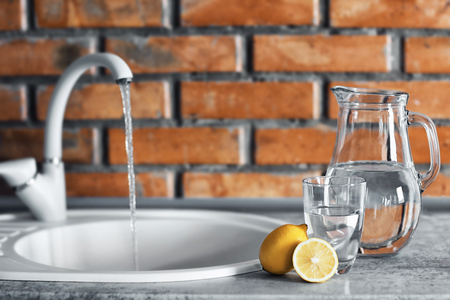 Jar with water and lemon on kitchen tableの写真素材
