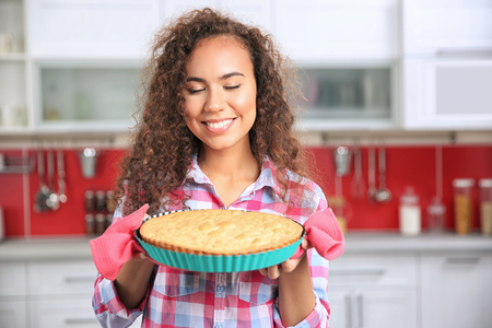 Beautiful African girl with cake in kitchenの写真素材