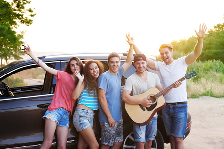 Cheerful friends with guitar near car, outdoorsの写真素材