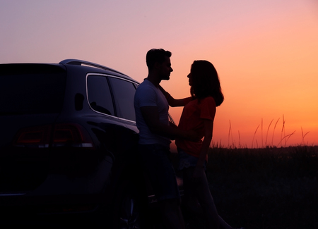 Young couple near car on sunset backgroundの写真素材