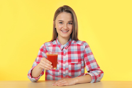 Young woman sitting at the table with a glass of fresh juiceの写真素材