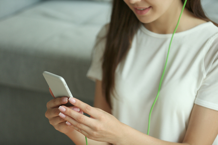 Woman listening to music on smartphone in the roomの写真素材