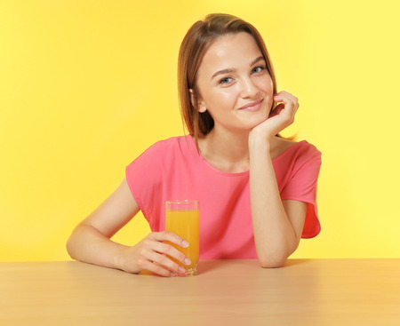 Young woman sitting at the table with a glass of fresh juiceの写真素材