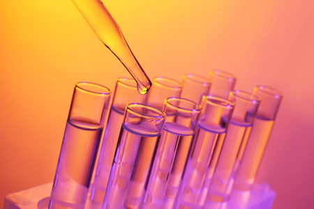 Close up of a pipette dropping a  sample into a test tube on colourful backgroundの写真素材