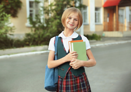 Cute schoolgirl with books on streetの写真素材