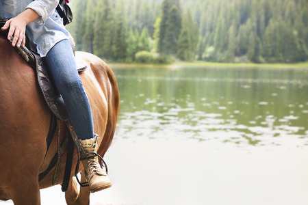 Girl riding horse near lakeの写真素材