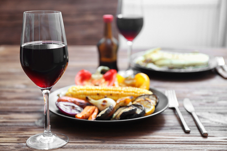 Grilled vegetables and glass of wine on wooden tableの写真素材