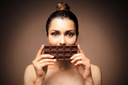 Beautiful girl with chocolate on brown background